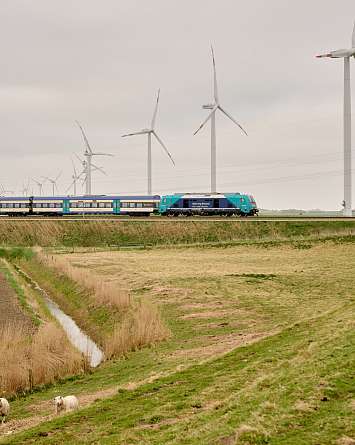 Bilder der Marschbahn mit Windrädern im Hintergrund